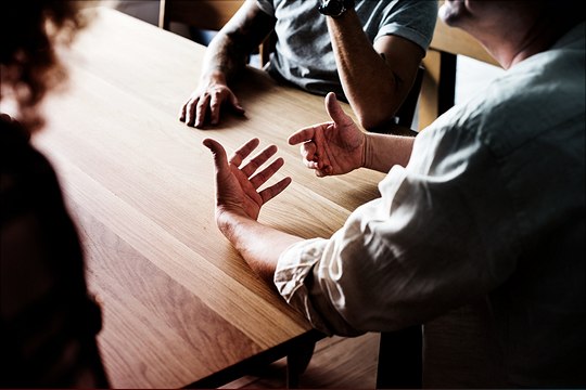 picture of three people in discussion sitting at a table