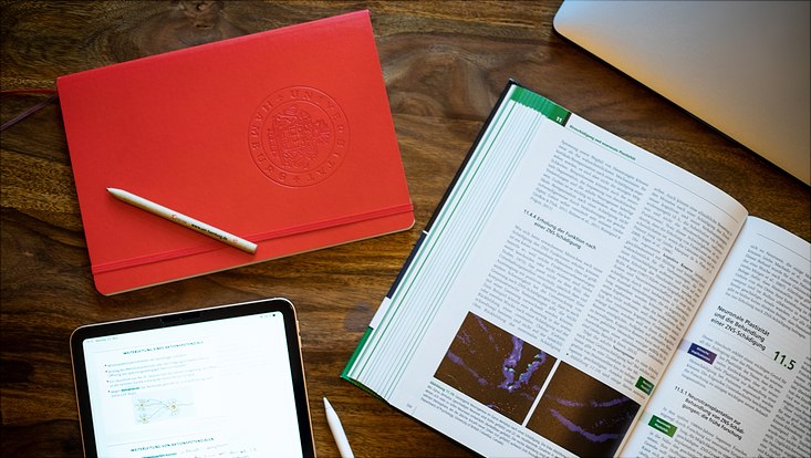 Rotes Notebook, Buch, Tablet mit Stift auf dem Tisch