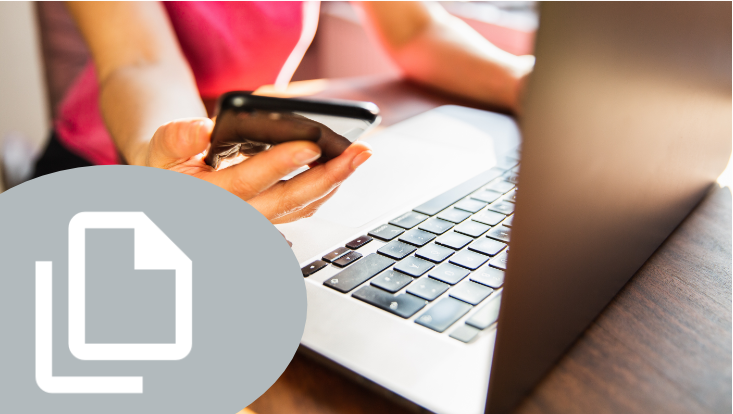 Mensch vor Laptop mit Smartphone/Person using laptop and smartphone