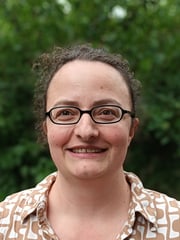 Portraitfoto von Stefanie Gäckle, in Hintergrund verwischte grüne Büsche